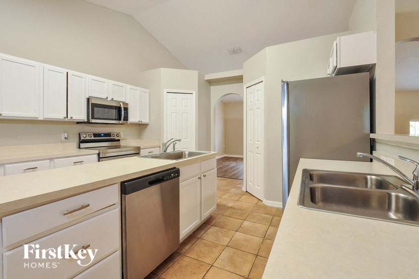 A kitchen with white cabinets and a stainless steel refrigerator.