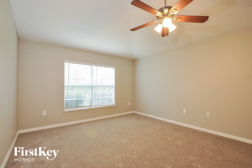 A room with a ceiling fan and a window with blinds.