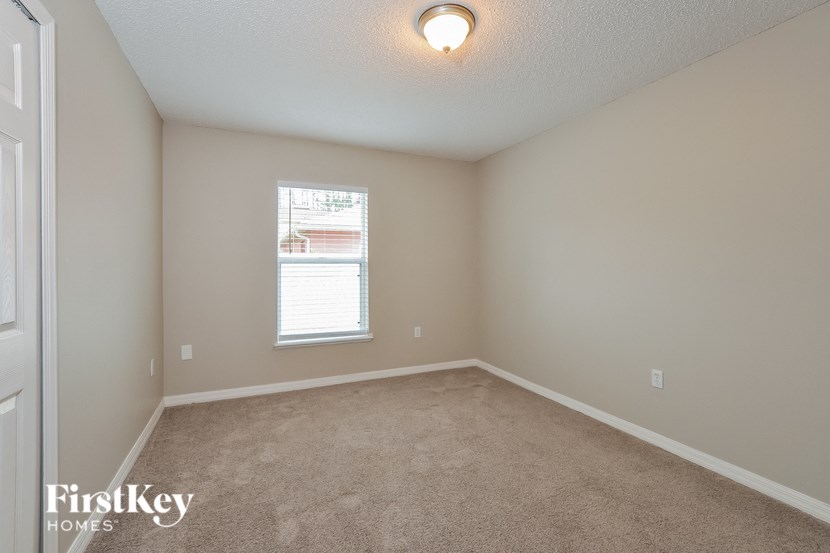 A room with a carpeted floor and a window with blinds.
