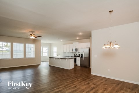 A spacious kitchen and living room with wood flooring and a hanging chandelier.