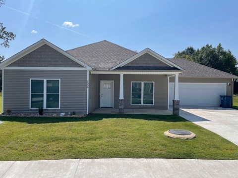 a gray house with a lawn and a driveway