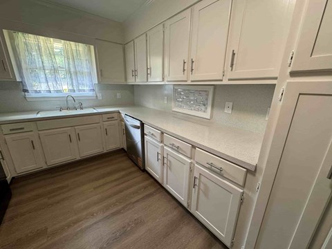 A kitchen with white cabinets and a wooden floor.