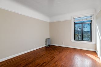 an empty living room with wood floors and a window