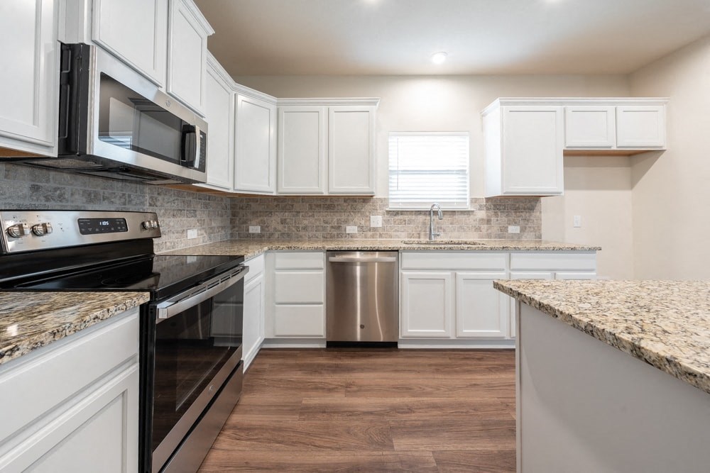 a kitchen with white cabinets and granite counter tops