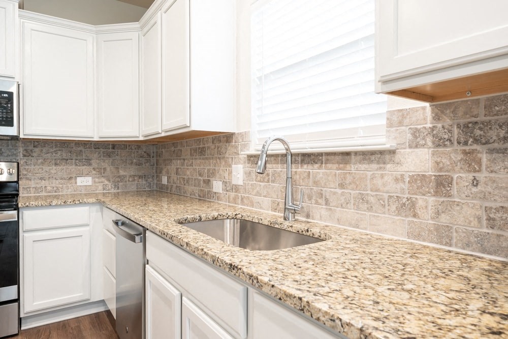 a kitchen with white cabinets and granite counter tops and a sink