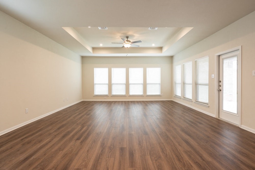 an empty living room with wood floors and a ceiling fan