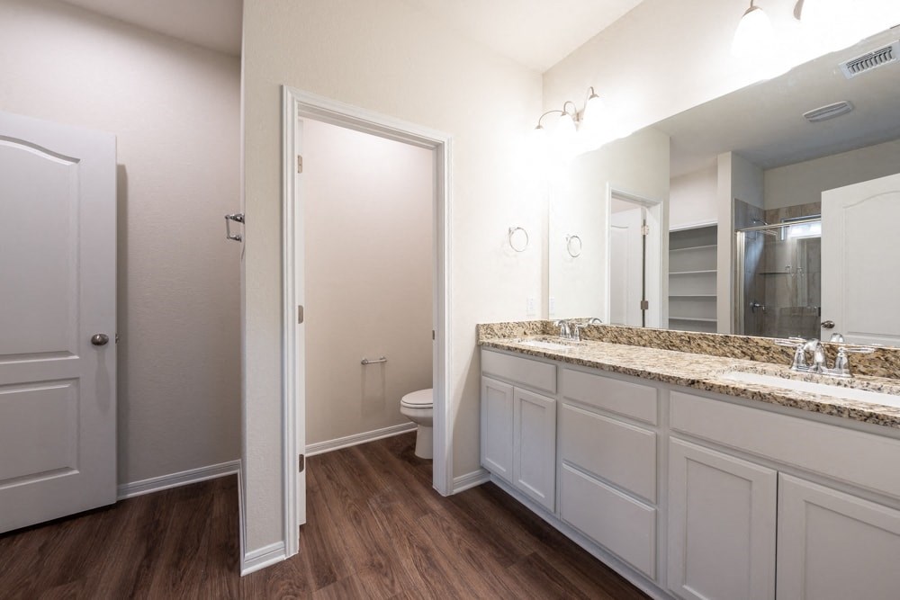 a bathroom with white cabinets and a mirror and a toilet