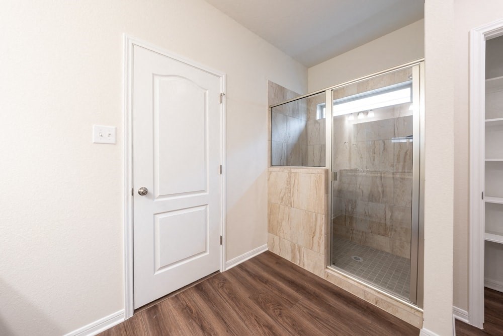an empty bathroom with a shower and a door