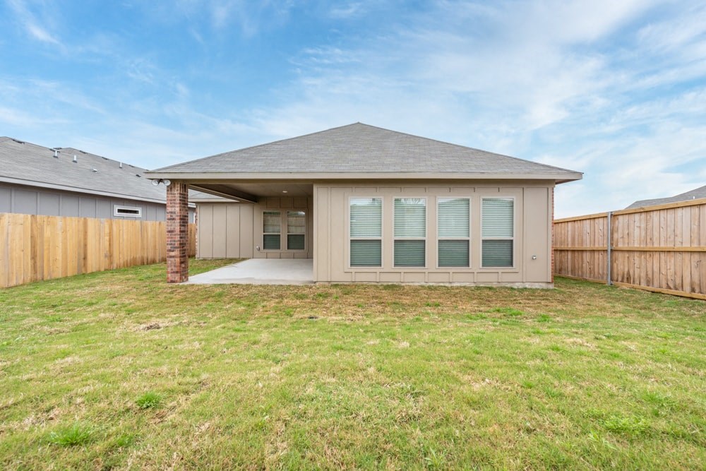 the back of a house with a yard and a fence