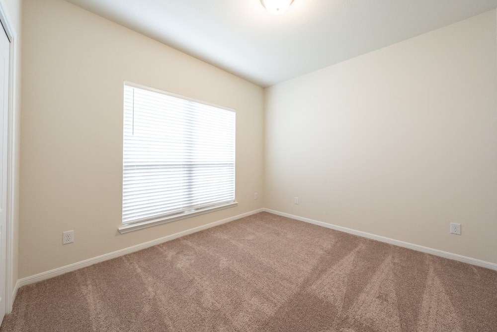 an empty living room with a large window and carpet