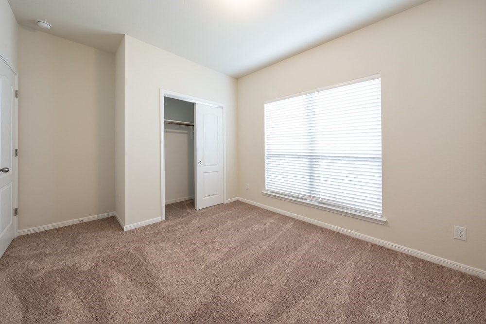 an empty living room with a large window and carpet