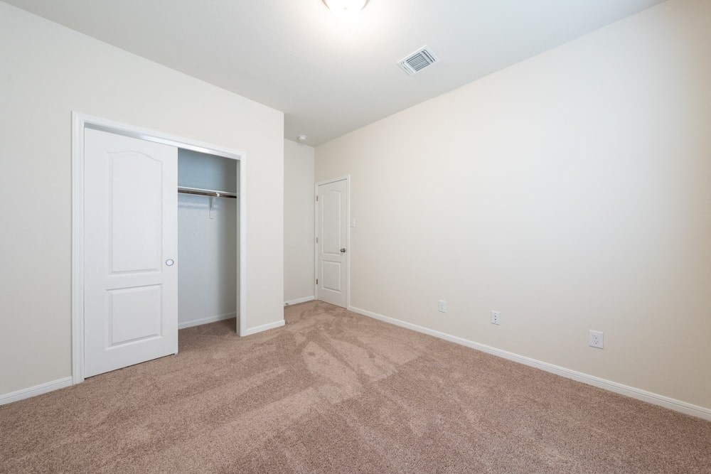 an empty living room with carpet and a closet