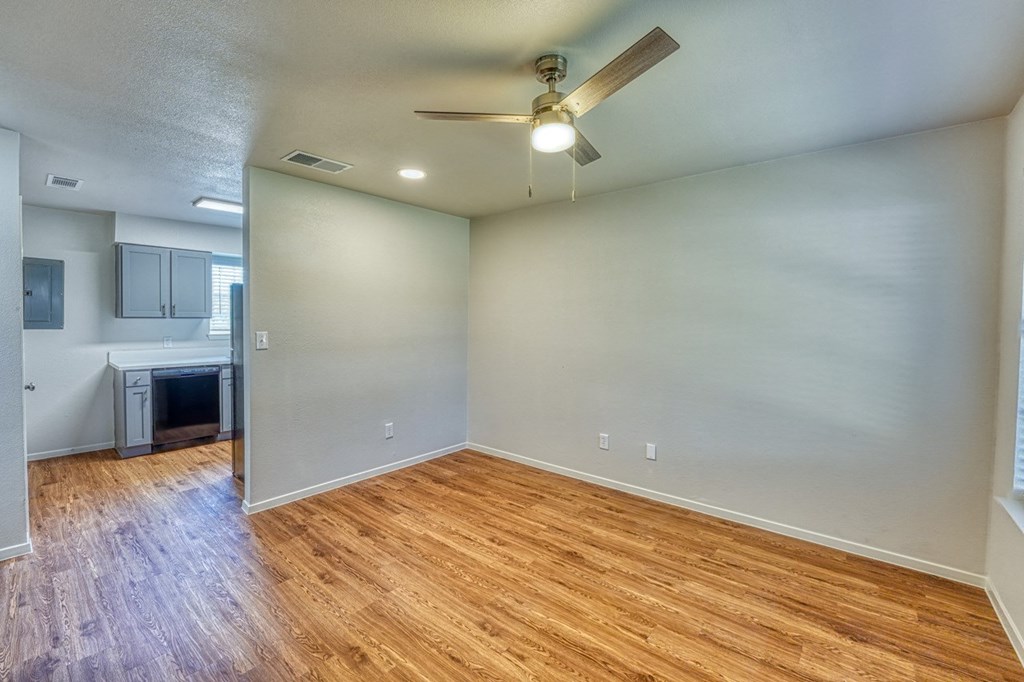 an empty living room with wood floors and a ceiling fan
