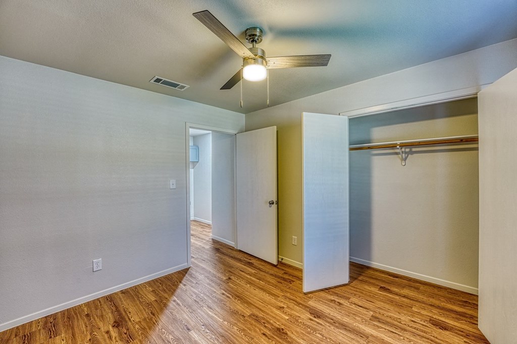 the living room and closet of an empty house with a ceiling fan