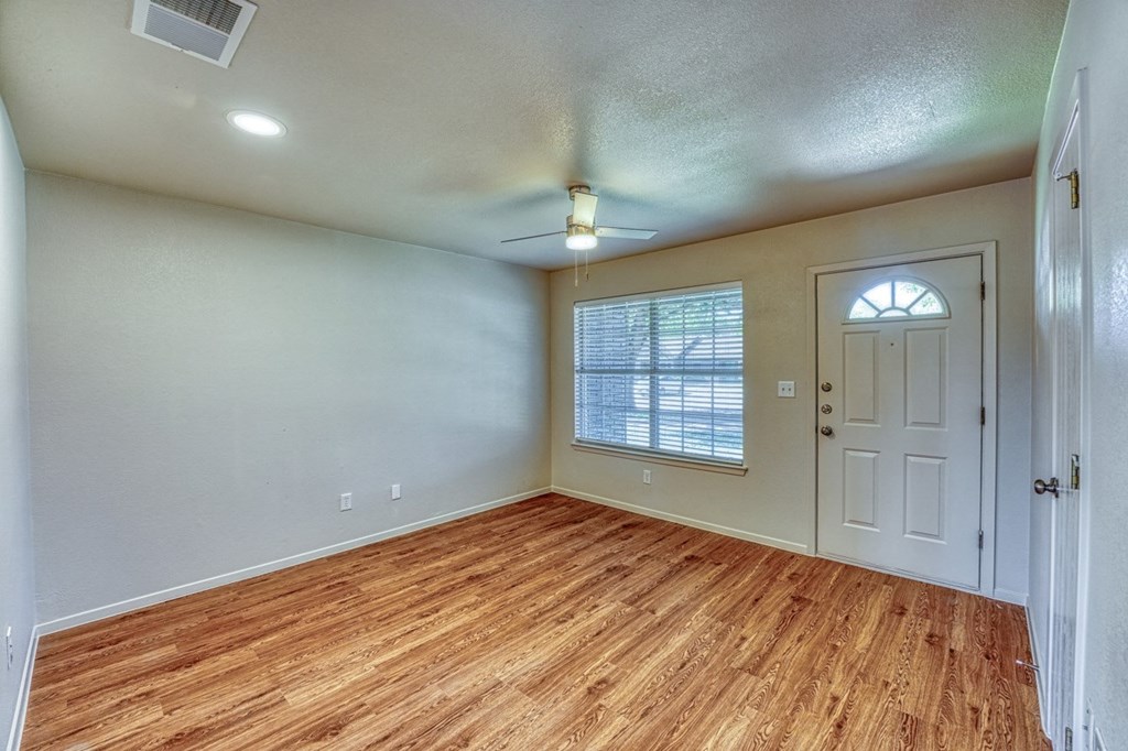 an empty living room with a hard wood floor and a white door
