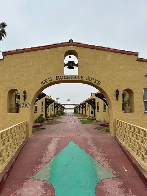 A pathway with a green arrow pointing forward under a bridge with Neu Rohelle Apis written on it.