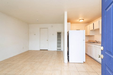 an empty kitchen with a white refrigerator and a blue door