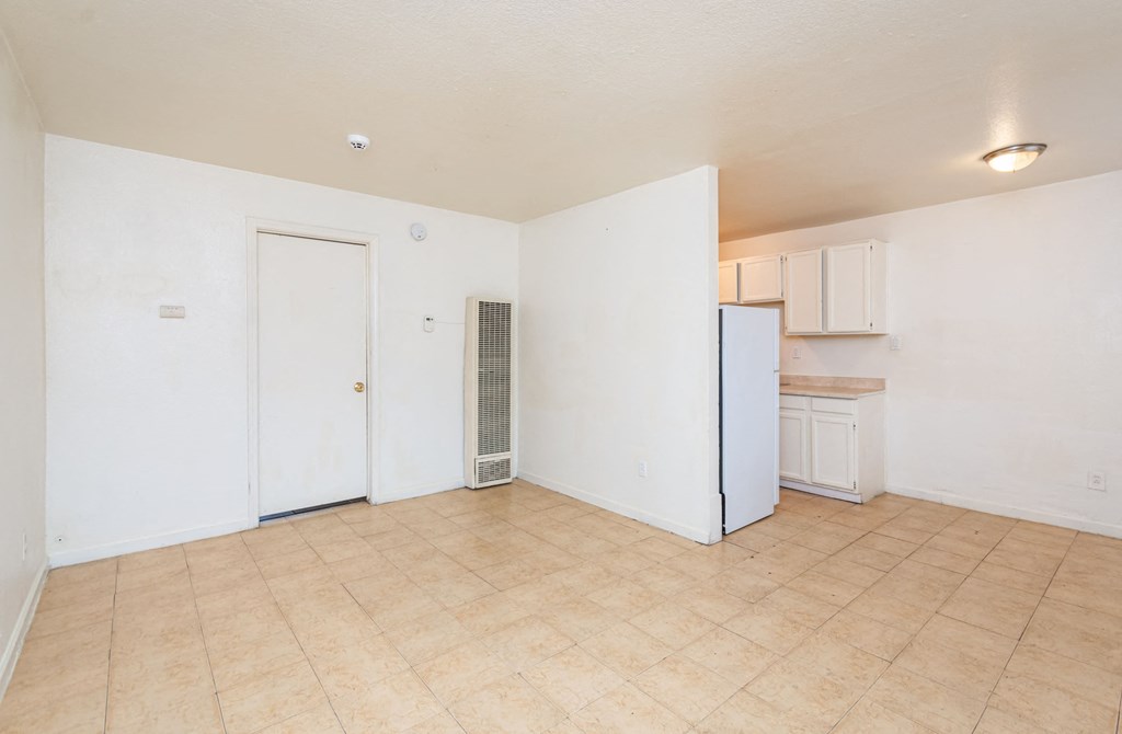 the living room and kitchen of an empty apartment with a refrigerator