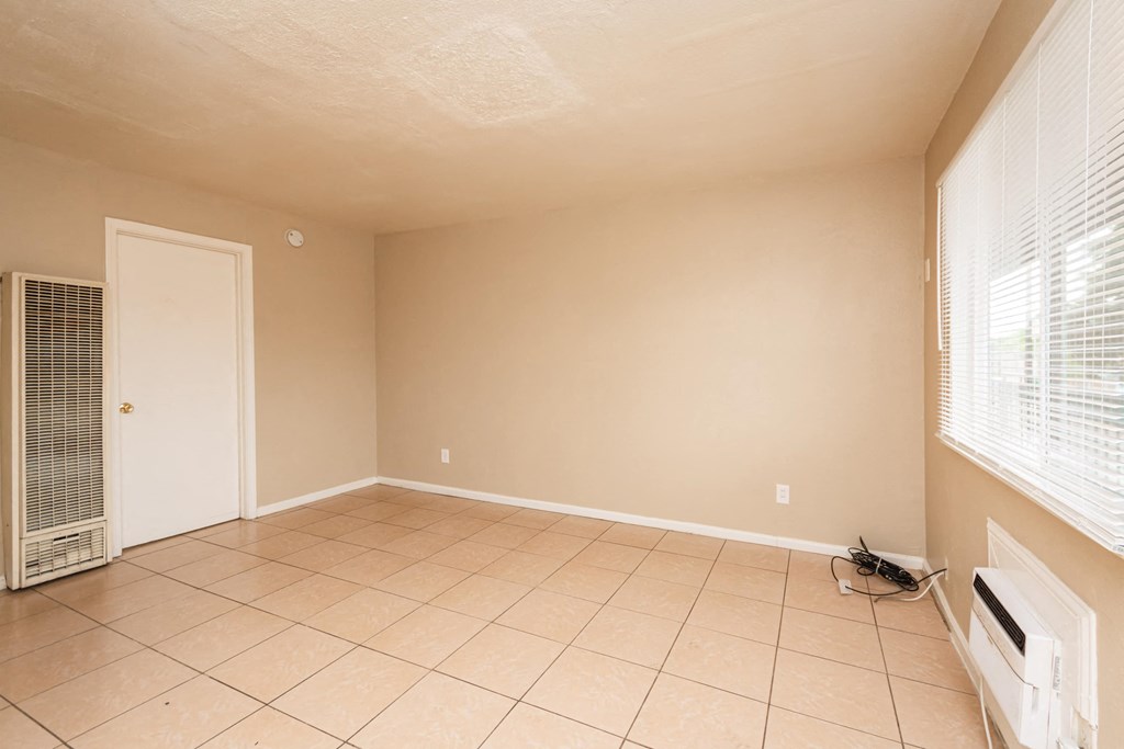 an empty living room with a tiled floor and a door