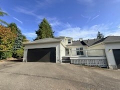 A house with a grey garage door is in front of a tree.