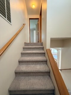 A staircase with a carpeted runner and wooden handrail.