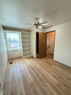 A room with a ceiling fan and wooden flooring.