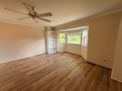 A room with a ceiling fan and wooden flooring.