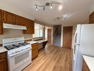 A kitchen with wooden cabinets and a white stove top oven.