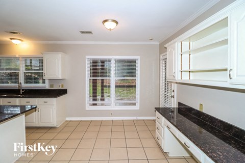 a kitchen with white cabinets and black counter tops and a window