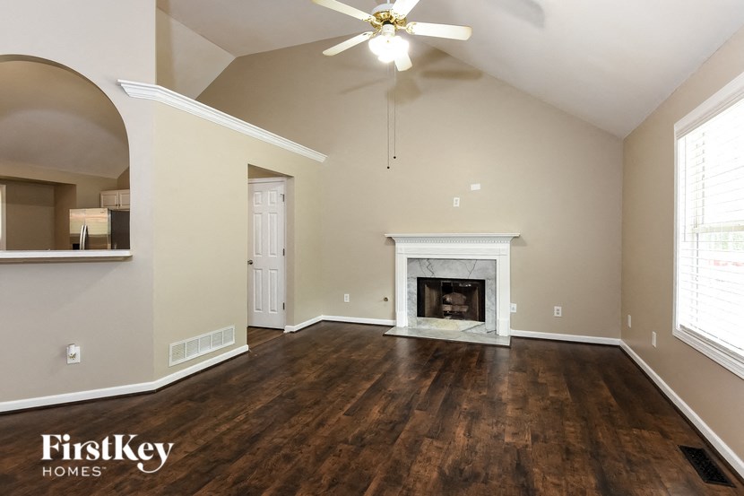 A spacious living room with a fireplace and a ceiling fan.