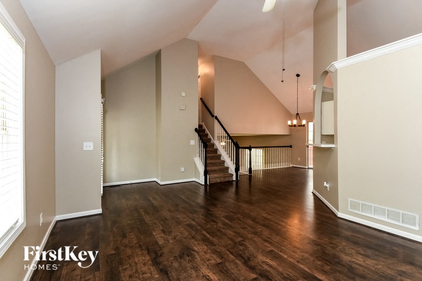 A spacious room with wooden floors and a staircase.
