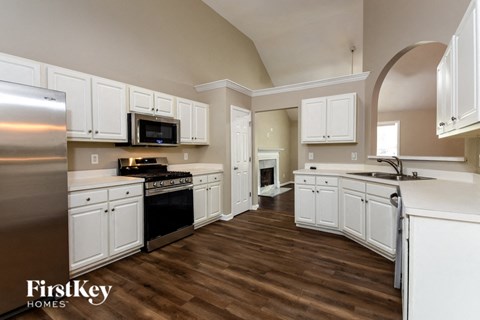 A kitchen with white cabinets and a wooden floor.