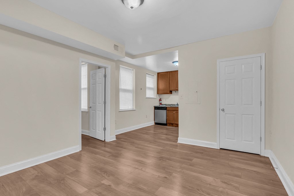 a renovated living room and kitchen with white walls and wood flooring