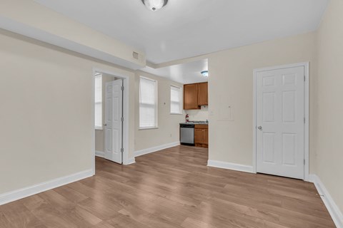a renovated living room and kitchen with white walls and wood flooring