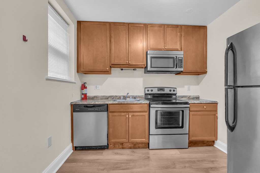 an empty kitchen with stainless steel appliances and wooden cabinets