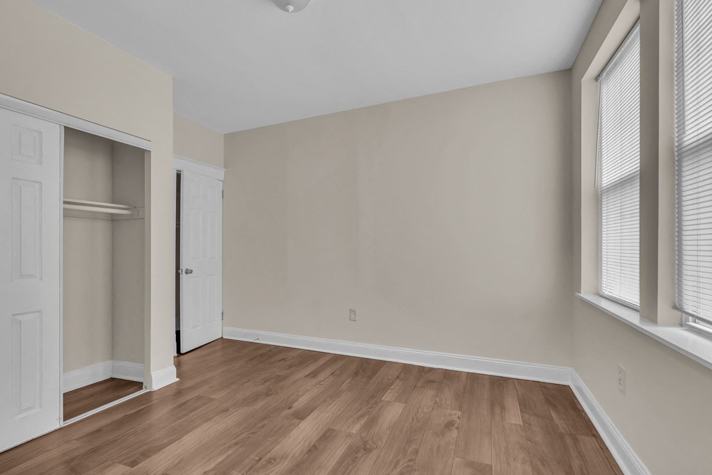 the living room of an apartment with wood flooring and a closet