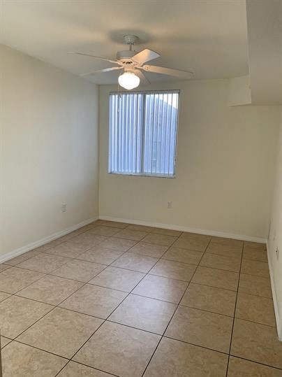 a empty room with a ceiling fan and a tiled floor