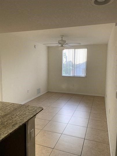 an empty living room with a ceiling fan and tiled floor