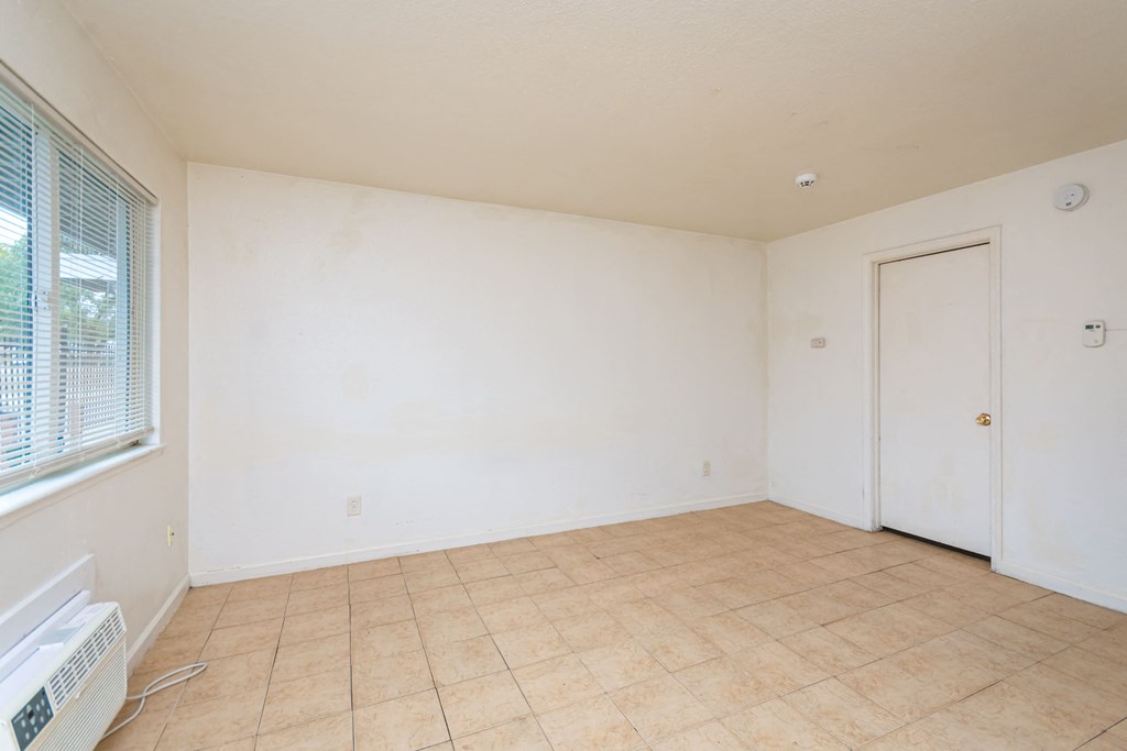 the living room of an empty home with white walls and a tiled floor