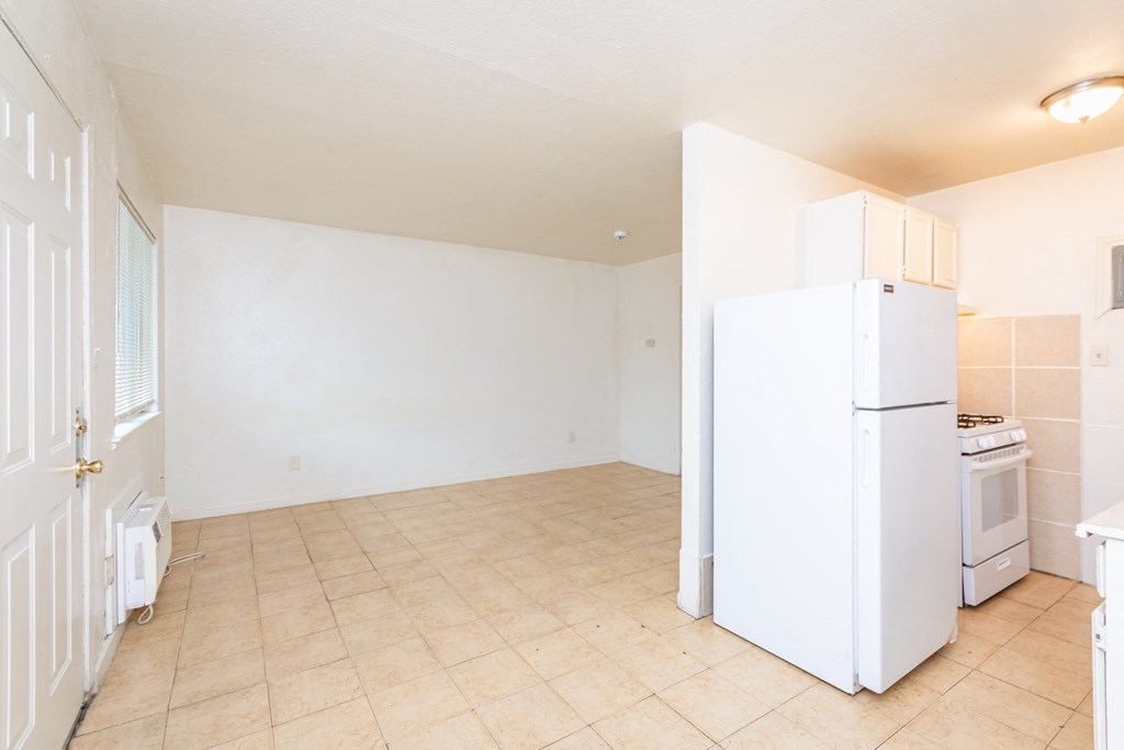 an empty kitchen with a refrigerator and a stove