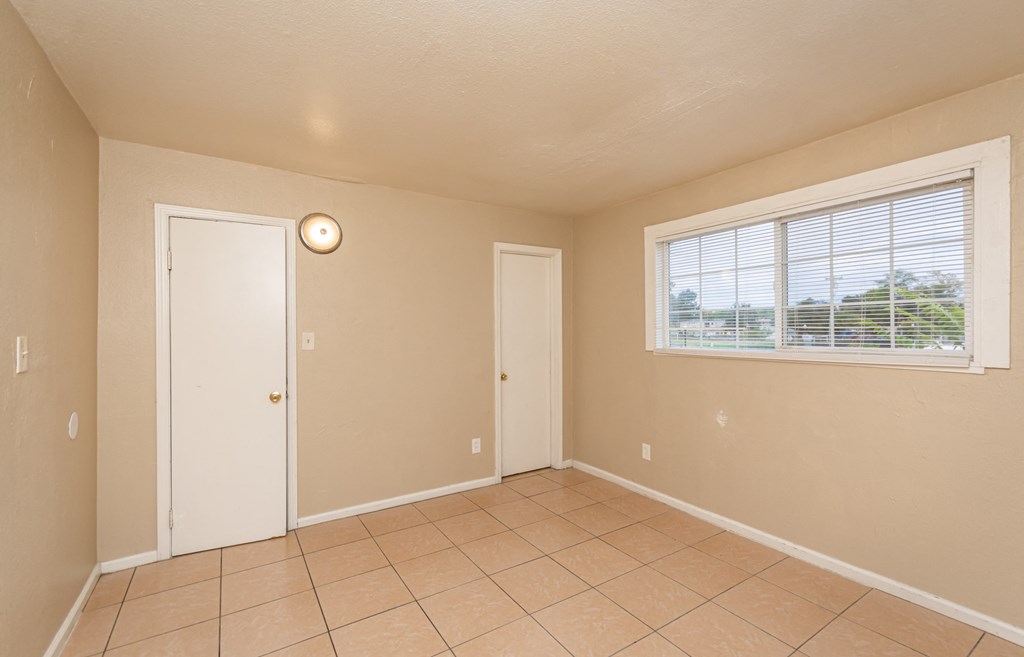 an empty living room with a large window and a tiled floor