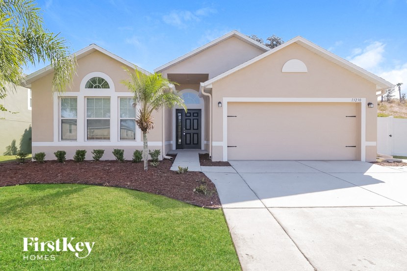 a beige house with a driveway and a palm tree