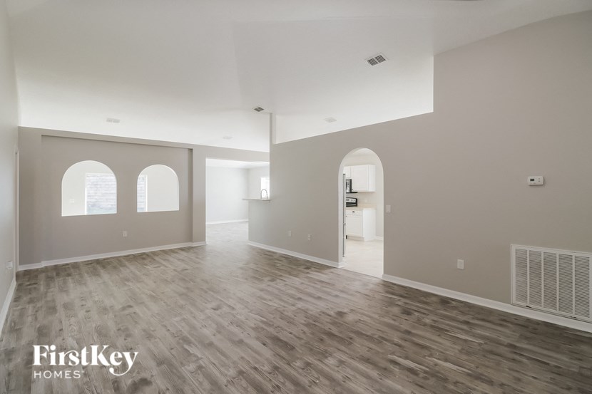 an empty living room with a wood floor and white walls