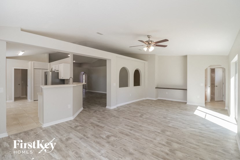 an empty living room and kitchen with a ceiling fan