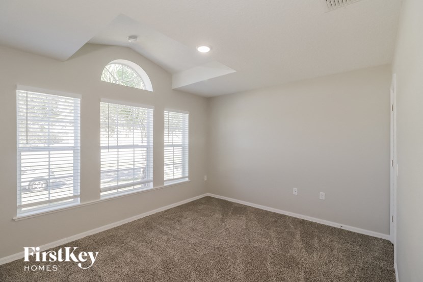 an empty room with three windows and a carpeted floor