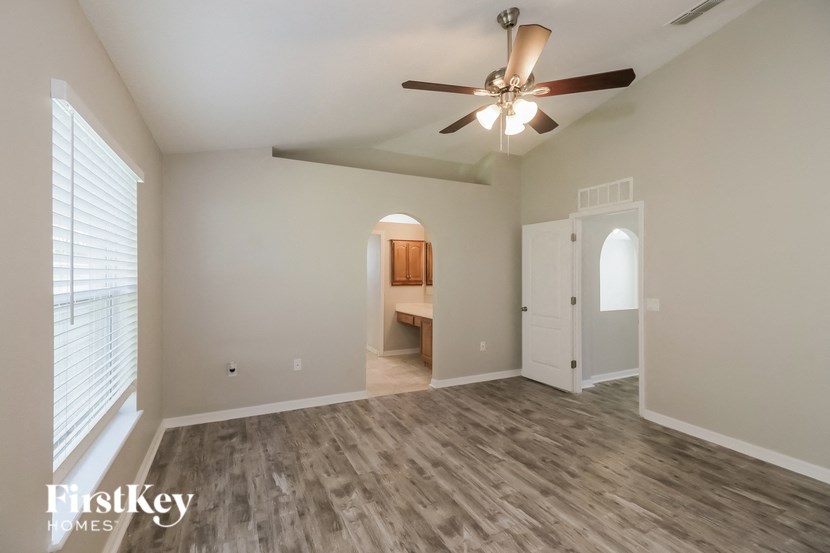 an empty living room with a ceiling fan and a door to a bathroom