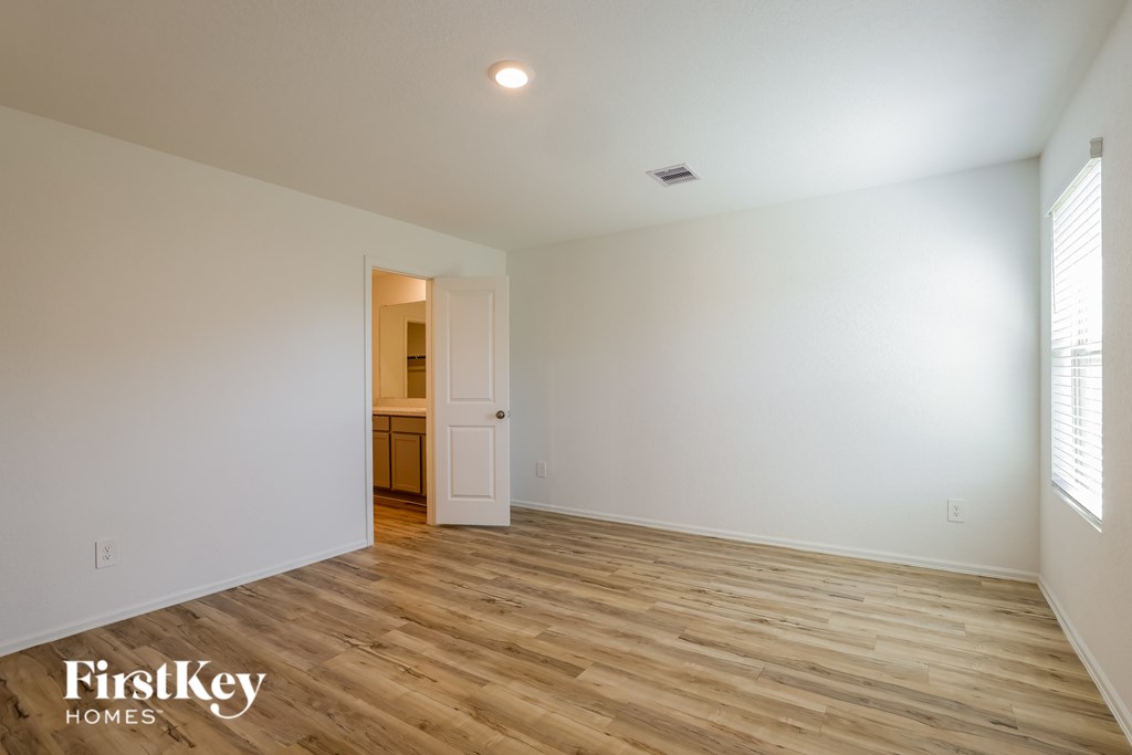 A room with wooden flooring and a doorway leading to another room.
