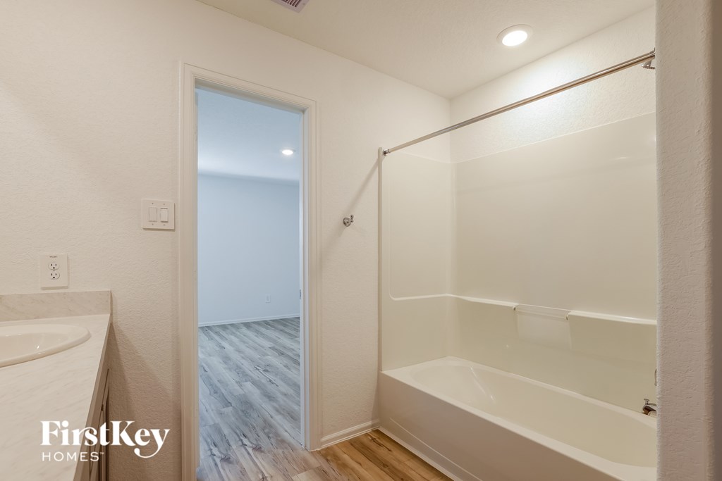 A white bathroom with a walk in shower and a door leading to a balcony.