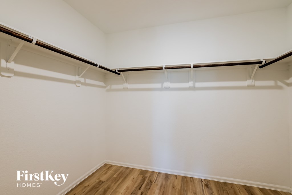 A white wall with a wooden floor and a black and white shelf.
