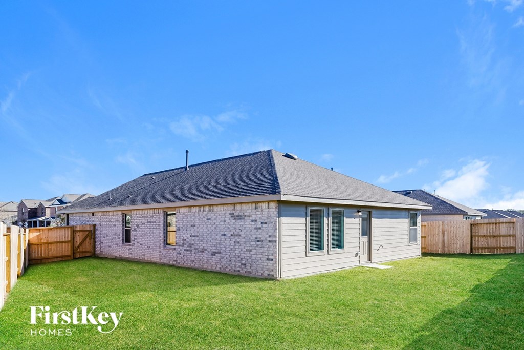 A house with a grey roof and a fence in front of it.